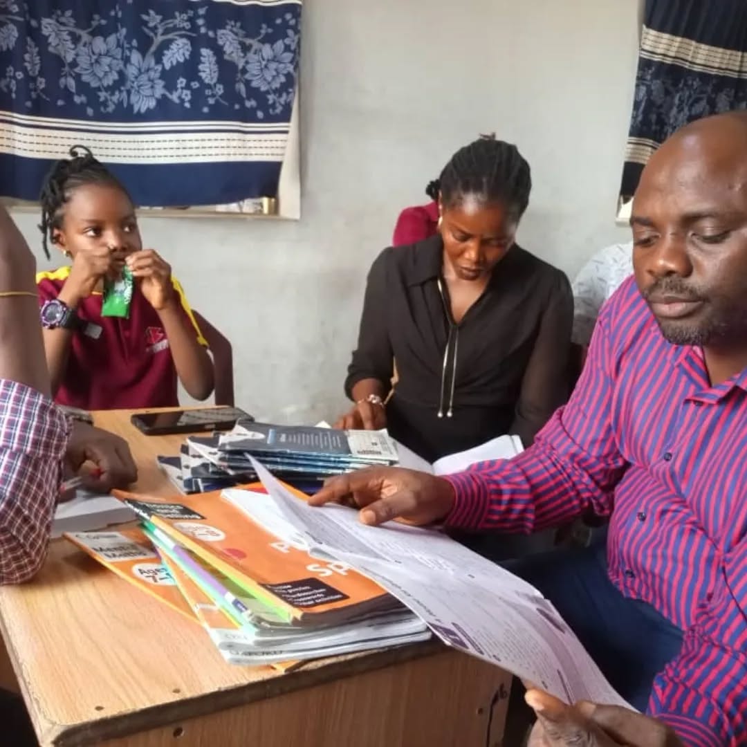 Parents reviewing school books and progress with a teacher